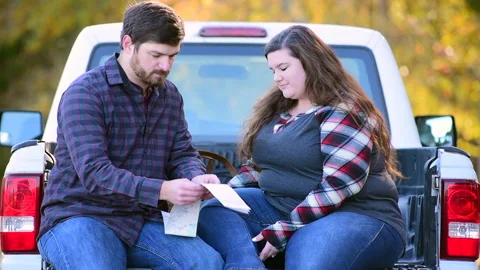 Couple at the back of a pick-up planning a trip while enjoying the fall colors 库存影片 143430483