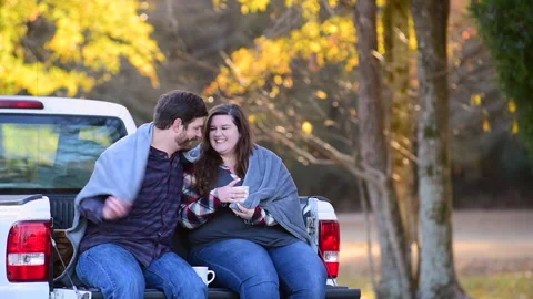 Couple at the back of a pick-up planning a trip while enjoying the fall colors 库存影片 143430788