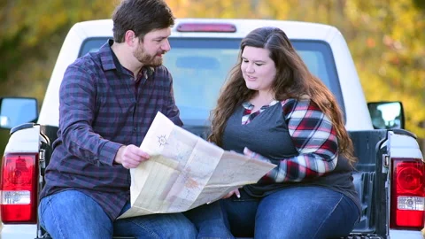 Couple at the back of a pick-up planning a trip while enjoying the fall colors 库存影片 143431175