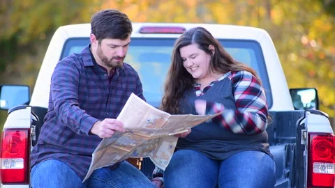 Couple at the back of a pick-up planning a trip while enjoying the fall colors 库存影片 143431224
