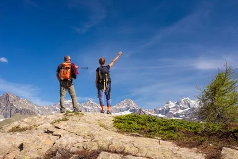 Couple with backpack on mountain top. Two people looking at scenic alpine lan Foto stock