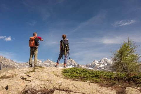 Couple with backpack on mountain top. Two people looking at scenic alpine lan Stock Photos