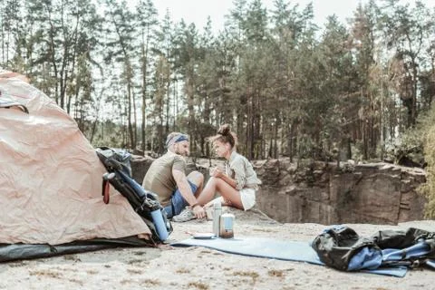 Couple of backpackers relaxing in forest while listening to music and drinking Foto stock