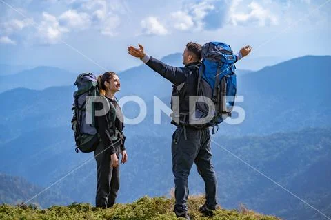 The couple with backpacks enjoying on a beautiful mountain landscape backgrou Stock Photos