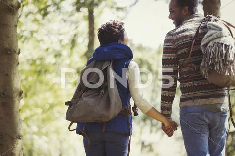 Couple with backpacks holding hands hiking in woods Stock Photos