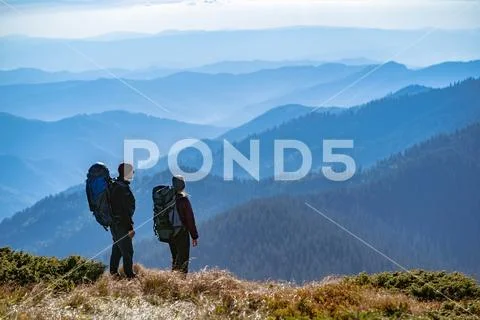 The couple with backpacks standing on the mountain with a beautiful view Stock Photos