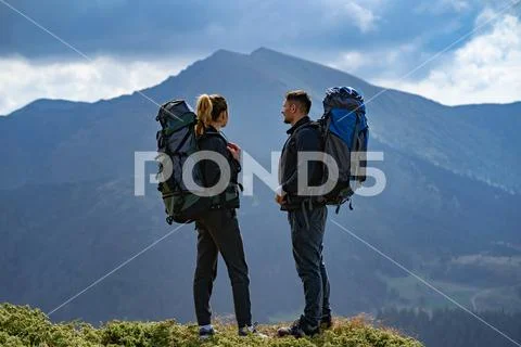The couple with backpacks standing on the mountain landscape background Stock Photos