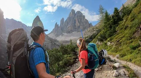 A couple with backpacks taking a selfie while hiking in Italian Dolomites. Stock Photos
