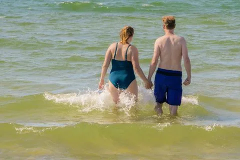 Couple backs in sea with wave splashes Stock Photos