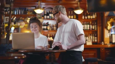 Couple of bar owners looking on laptop screen for online orders Stock Footage