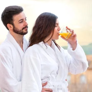 Couple in bathrobe drinking fruit juice. Stock Photos