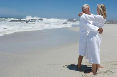 Couple in bathrobe, embracing on the beach Stock Photos
