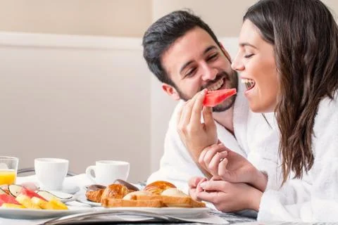 Couple in bathrobe having fun eating fruit. Stock Photos