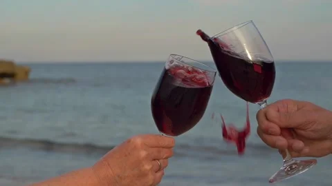 A couple on the beach clinking glasses of red wine and the wine flies. Stock Footage 135350746