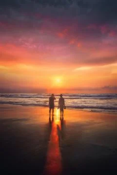 Couple on beach looking at sunset Stock Photos
