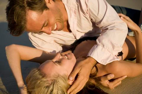 A couple at the beach lying in the sand Stock Photos