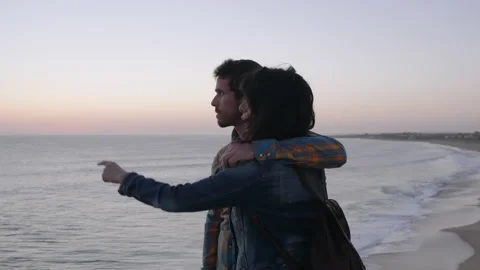 Couple on beach talking and pointing at sea Video stock 131157465