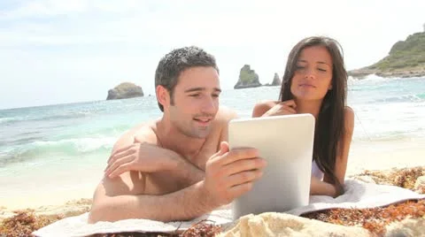 Couple at the beach using electronic tablet Stock Footage 14827575