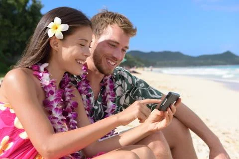 Couple on beach using smart phone on Hawaii Stock Photos