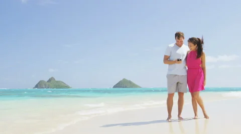 Couple on beach vacation using smart phone app - people having fun 스톡 동영상 60687953