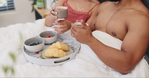 Couple in bed, breakfast and tea with cheers, love and commitment with food Stockbeeldmateriaal 306506770