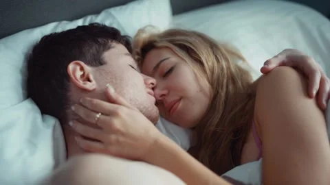 Couple in bed gently stroking each other . white sheets, delicate tones Stock Footage 235495782
