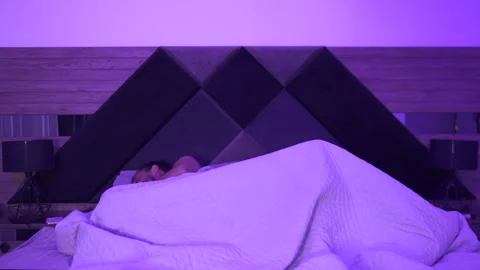 A couple in bed suddenly wakes up thinking they are late. He looks at her Stock Footage 283784242