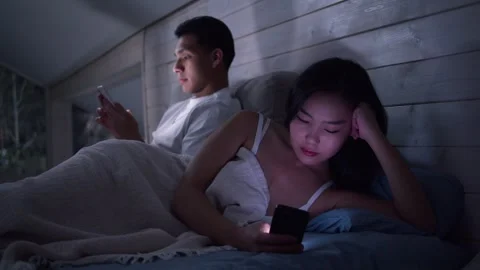 Couple in bed using smartphone, night bedroom light. Addiction social media. Stock Footage 327706381