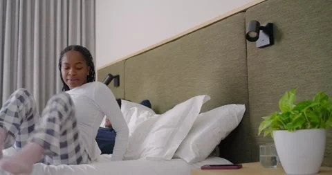 Couple in bed, woman checking red phone, sitting up, grabbing glass, drinking Stock Footage 346644249