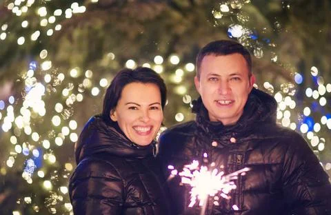 Couple with Bengal light looking at camera outside over Christmas backgrou... Fotos Stock