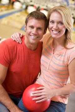 Couple in bowling alley holding ball and smiling Stock Photos