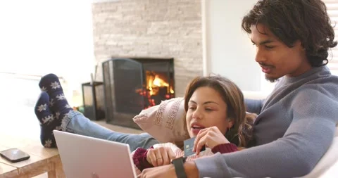 Couple browsing site, reaching for credit card, typing purchase info on laptop Stock Footage 336058495