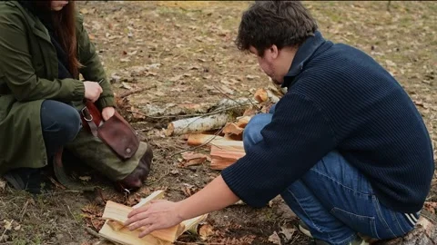 Couple building a fire structure from firewood in the forest 库存影片 334680642