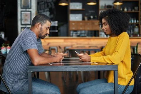 Couple at café table using mobile phones Stock Photos