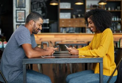 Couple at cafe table using mobile phones Stock Photos