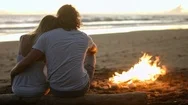 Couple By Campfire Looking At Ocean Stock Footage