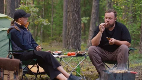 Couple camping in forest drinking beer and eating outdoors Stock Footage 327136024