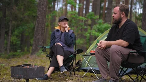Couple camping in forest having an animated conversation Stock Footage 327130647