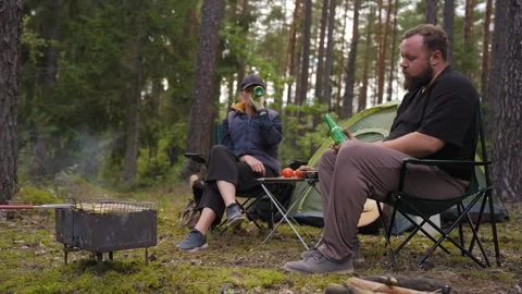 Couple camping in forest talking and grilling food Stock Footage 327132402