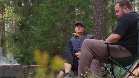 Couple camping in forest talking and drinking beer Stock Footage 327136114