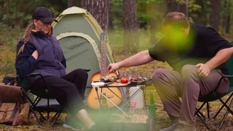Couple camping in forest talking and drinking beer Stock Footage 327136129