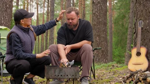 Couple camping in pine forest enjoying campfire and beer Stock Footage 327134800