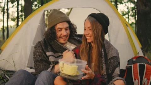 A couple is camping together in nature while enjoying delicious food inside a Stock Footage 285372259