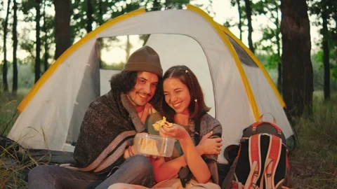 A couple is camping together in nature while enjoying delicious food inside a Stock Footage 285374432