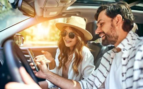 A couple in the car are watching navigation maps on the phone. Buying a car.  Stock Photos