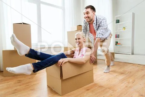 Couple with cardboard boxes having fun at new home Stock Photos