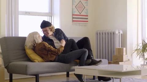 Couple Carry A Load Of Stuff Into New Apartment, Then Collapse On The Couch Video stock 62309343