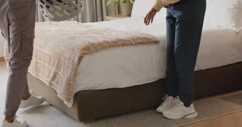 Couple carrying laundry basket, placing on bed at home, sorting clothes to fold Stock Footage 346644643