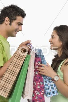 Couple carrying shopping bags and smiling Stock Photos