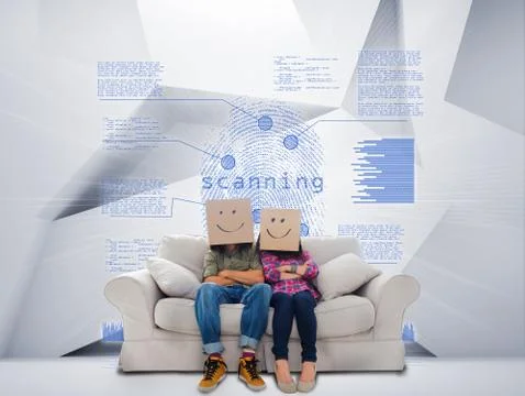Couple with cartons on head sitting on couch under blue holographic finger print Stock Photos